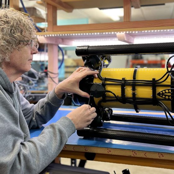 Craig Anderson with Boxfish AUV on the desk, AUV mounted with DVL and grabber